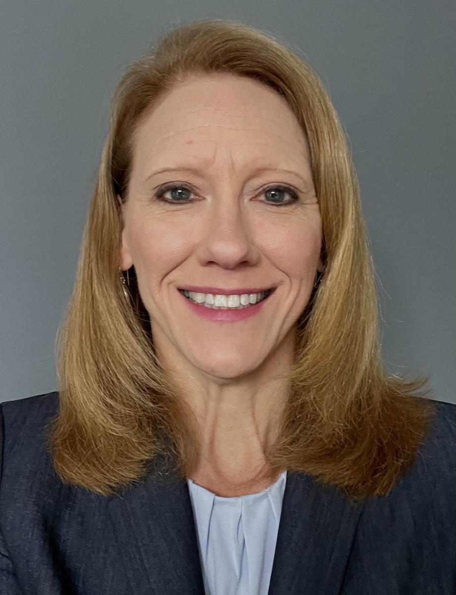 image of a woman's head and shoulders showing a blond light skinned person with shoulder length hair smiling wearing a navy suit jacket and white shirt 